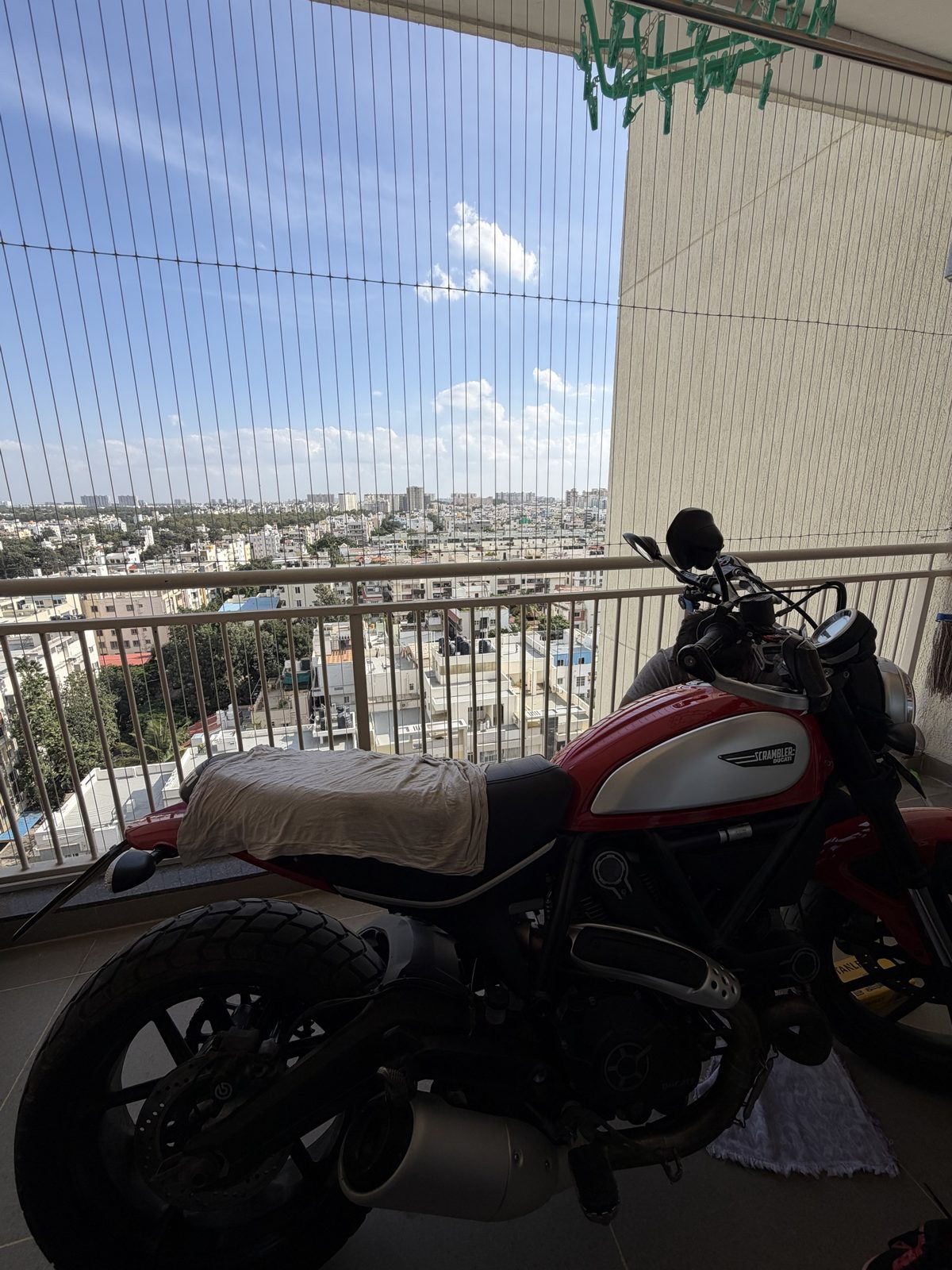 The Scrambler parked on a high-rise balcony, with the city spread out behind the railing